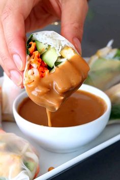 a person dipping sauce onto some food on a plate