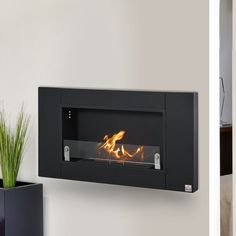 a black wall mounted fireplace next to a potted plant