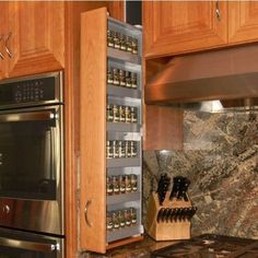 a kitchen with wooden cabinets and stainless steel stove top oven next to an open spice rack