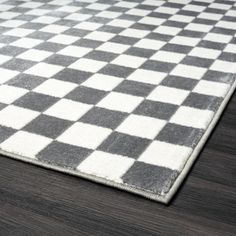 a black and white checkered rug on a wooden floor