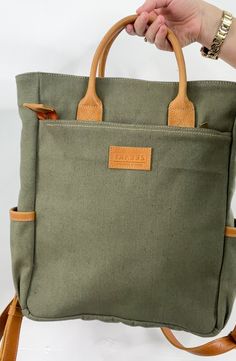 Zelaki Leather Co Canvas Backpack in Olive The Canvas Backpack is a durable and gender-neutral bag that can serve many purposes. With its sturdy design, it can withstand daily wear and tear, making it a reliable choice for those on the go. Details: -Ethically & sustainably made in Ethiopia-Canvas & full-grain leather-Canvas interior-One outside zipping pocket (12"x12") -Zipper closure -Two cupholders -One interior compartment (13"x12")-Adjustable straps-15"H x 12"W x 4"D Practical Backpack For On-the-go, Khaki Satchel With Top Carry Handle For Daily Use, Khaki Travel Bag With Top Carry Handle, Khaki Large Capacity Shoulder Backpack, Casual Daily Use Backpack With Top Carry Handle, Khaki Softback Shoulder Bag For Everyday, Everyday Use Khaki Softback Shoulder Bag, Standard Backpack For Daily Use, Khaki Satchel Backpack With Large Capacity