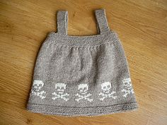 a gray knitted bag with skulls and bones on it sitting on a wooden floor