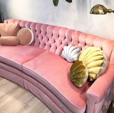 a pink couch with pillows sitting on top of it