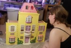 a woman looking at a doll house made out of plastic