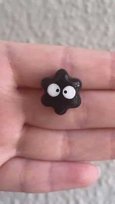 a hand holding a tiny black object with eyes