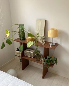 a room with a bed, plant and lamp on the side table next to it