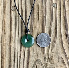 A donut shaped, shiny green jade pendant is hand knotted on leather cord for a bit of a good luck charm. Jade is known as the lucky gemstone and is also considered a stone of wealth. A sliding knot closure lets you wear the necklace long or short depending on your mood! Pendant is slightly smaller than a quarter. Jade comes in variety of shades of green. Your piece may vary from those pictured. At its longest, the necklace is about 27" in length, not including the pendant. Leather jewelry should Adjustable Jade Jewelry With Round Pendant, Adjustable Round Jade Pendant Jewelry, Adjustable Jade Necklace For Good Luck, Adjustable Green Necklace With Waxed Cord, Green Waxed Cord Jewelry With Sliding Knot, Adjustable Green Waxed Cord Necklace, Adjustable Round Aventurine Necklace, Sliding Knot Closure, Donut Shape