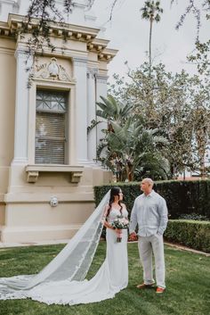 a man and woman standing in front of a building with a veil on their wedding day