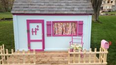 a doll house with pink shutters on the front door and windows in the back