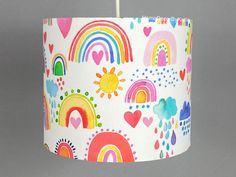 a colorful lamp shade with hearts, rainbows, and clouds on white paper hanging from the ceiling