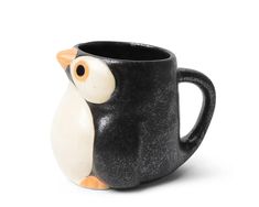 a black and white ceramic owl mug with an orange beak on it's head