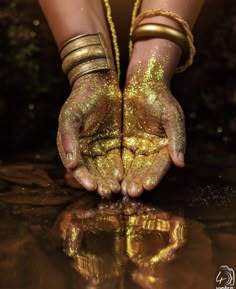 a woman's hands are covered in gold glitter and holding onto the ground with her hands