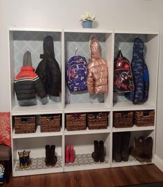 a white shelf filled with lots of coats and backpacks on top of it's sides