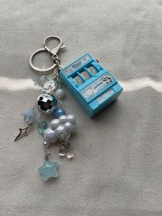 a keychain with charms attached to it sitting on a white surface next to a blue box