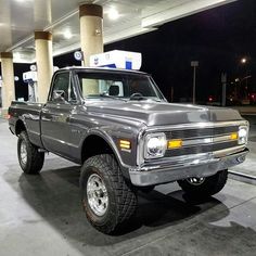 an old pickup truck parked in a gas station