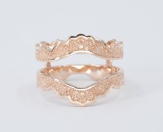 two gold wedding bands with intricate designs on each band, set against a white background