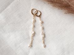 These long pearl earrings are so dainty and cute. In these 14k gold-plated earrings, there are small genuine freshwater pearls in different shapes. Lightweight, very pretty earrings.  Length: 2.8 in = 7,1 cm (including the ear wire) ♥ Jewelry care ♥ It's important to keep your jewelry dry: Take it off before taking a shower, bath, swimming or exercising. Always apply your makeup, perfume and hairspray before putting on your jewelry. Store your jewelry somewhere dry (not in the bathroom). See my whole jewelry collection: https://www.etsy.com/shop/Tazelry Dainty Pearl White 14k Gold Filled Pearl Earrings, Minimalist Pearl Chain 14k Gold Filled Earrings, Minimalist Pearl Chain Earrings In 14k Gold Filled, Dainty Pearl White Earrings, Minimalist 14k Gold Filled Pearl Chain Earrings, Delicate 14k Gold Filled Earrings With Pearl Chain, Handmade Delicate 14k Gold-filled Pearl Earrings, Delicate Pearl Chain Earrings In 14k Gold, Dainty Pearl Charm Linear Earrings For Wedding