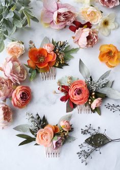 several different types of flowers and leaves on a white table with some hair combs