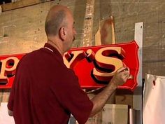 a man is painting the letters on a sign