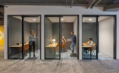 three people standing in an office with glass walls