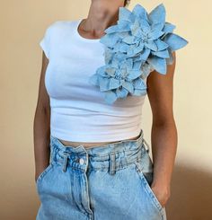 a woman in white shirt and jeans with flower on her chest