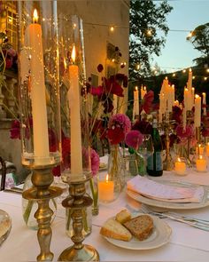 a table with candles, plates and flowers on it