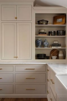 a kitchen with white cabinets and gold pulls on the cupboards, along with wooden flooring