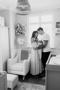 a man and woman standing next to each other in a room with a baby crib