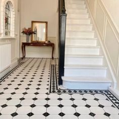 an entryway with black and white tile flooring next to a stair case in a home