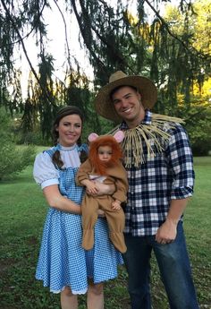 a man and woman dressed up as scarecrows pose for a photo in front of a tree