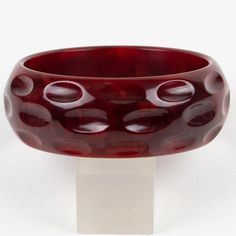 This is part of Chairish’s Costume Jewelry assortment.  This is a stunning crimson-red marble Bakelite bracelet bangle. It features a chunky domed shape with geometric and deeply carved designs. The color is an intense red marble tone with cloudy swirling.  Measurements: Inside across is 2.50 in diameter (6.3 cm) - outside across is 3 in diameter (7.7 cm) - width is 1.07 in (2.7 cm) - The inner circumference of the bracelet is 7.79 in (19.78 cm).  Please see the measurements noted above in the d Elegant Handmade Red Bangle, Affordable Handmade Red Bangle, Red Glass Bangles, Vintage Handmade Red Bangle, Vintage Red Adjustable Bangle, Bakelite Bracelets, Carved Designs, Costume Jewelry, Bangle Bracelets