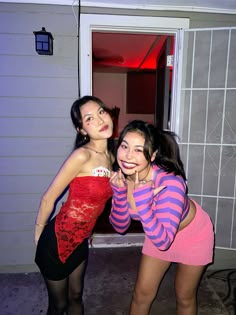 two young women posing for the camera in front of a door with their arms around each other