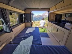 a man sitting in the back of a camper looking out at mountains and valleys