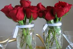 two mason jars with roses in them on a table