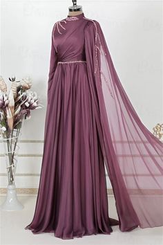 Step into elegance with this exquisite Full-Length Evening Gown. Crafted in a rich shade of deep plum, this gown features a luxurious chiffon fabric that drapes beautifully, creating a silhouette that flatters every figure. The delicate beading along the high neckline and waist adds a touch of sparkle, while the sweeping floor-length skirt ensures you make a grand entrance at any event.The intricate detailing on this gown sets it apart. A unique cross-body draping design adds depth and sophistication, while the sheer cape sleeve, adorned with beaded accents, cascades gracefully, offering a touch of drama and elegance. The concealed back zipper ensures a seamless fit, making this gown as comfortable as it is stunning.Ideal for evening soirées, weddings, or formal occasions, this Full-Length Purple Chiffon Dress For Banquets, Elegant Maxi Length Georgette Evening Dress, Formal Purple Chiffon Maxi Dress, Elegant Maxi Length Evening Dress In Georgette, Chiffon Floor-length Maxi Dress For Banquet, Floor-length Chiffon Maxi Dress For Banquet, Floor-length Chiffon Maxi Dress For Banquets, Elegant Purple Georgette Dress, Chiffon Gown For Evening