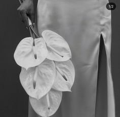 a woman holding a bunch of flowers in her right hand and the bottom half of her skirt