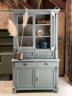 a blue china cabinet with some plants in it