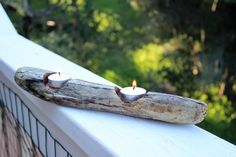 two candles are placed on a piece of wood