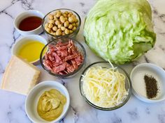 lettuce, meats, and other ingredients are arranged on a marble surface