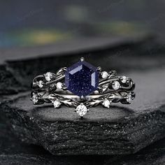 a ring with a blue stone surrounded by white diamonds on top of a black rock