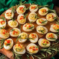 deviled eggs are arranged on a wooden platter with rosemary garnishes