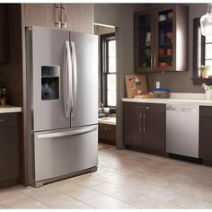 a stainless steel refrigerator in a kitchen with brown cabinets and tile flooring, along with white counter tops