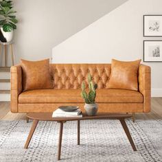 a brown leather couch sitting on top of a wooden table next to a potted cactus