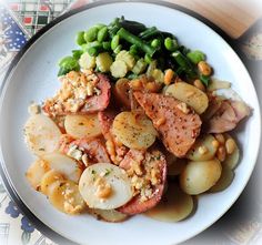 a white plate topped with meat, potatoes and green beans on top of a table