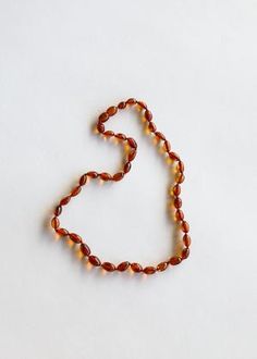 a necklace made out of beads on a white surface with the word love spelled in small letters