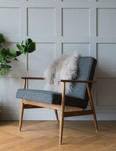 a chair with a fur pillow on it in front of a white paneled wall