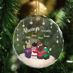 an ornament hanging from a christmas tree with three people sitting on the ground