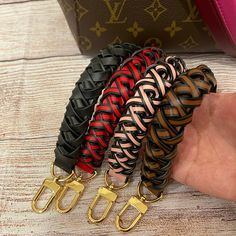 four different colored braided leather bracelets in front of a louis vuitton bag