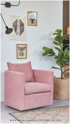 a living room with pink furniture and pictures on the wall above it, along with a potted plant