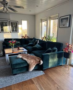 a living room with green velvet couches and pictures on the wall above them,